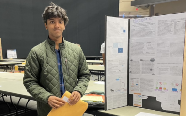 Sachchit posing with a presentation board on his cancer detection tool.